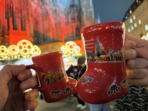 Mugs of punch with a Xmas market and gothic cathedral behind